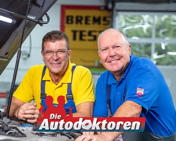 Die Autodoktoren Hans-Jürgen Faul und Holger Parsch in in Arbeitskleidung